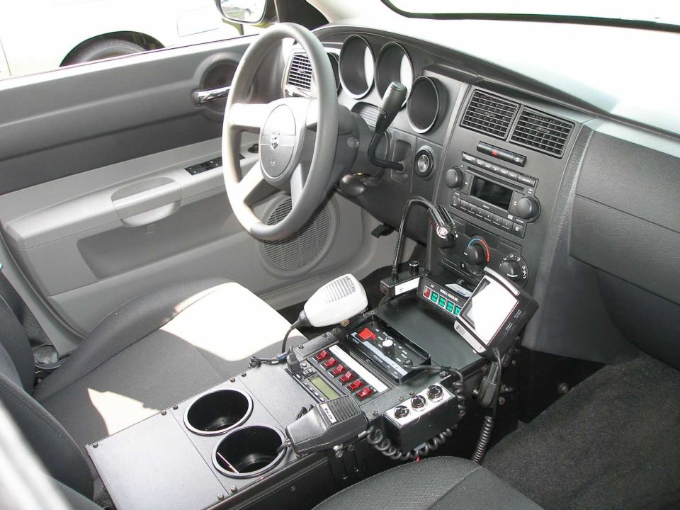 Police sedan interior with center console radio equipment, siren controls and steering wheel