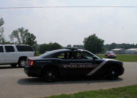 1998 Ford Crown Victoria - A black police car with markings is parked next to a white SUV.