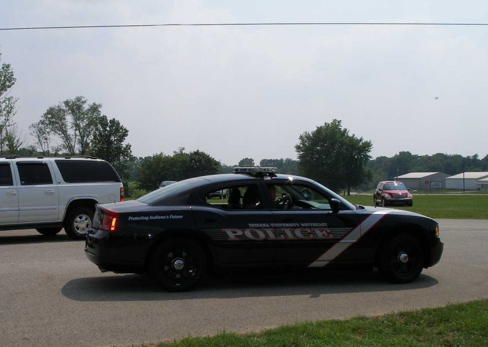 Black Indiana University Southeast Police Dodge Charger sedan with light bar, side view on pavement