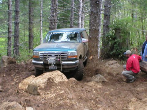 1978 Ford Bronco - Ford Bronco attempts to clear a large rock on a muddy, wooded trail.
