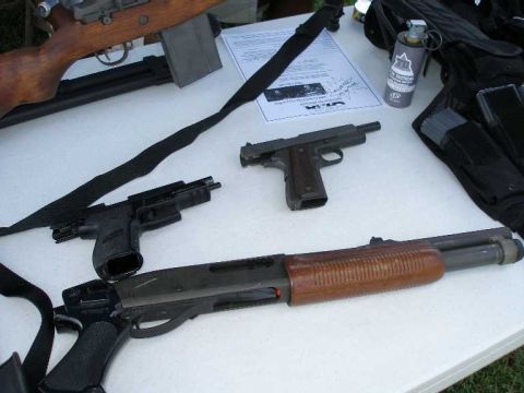 1998 Ford Crown Victoria - A collection of firearms and tactical equipment displayed on a table.