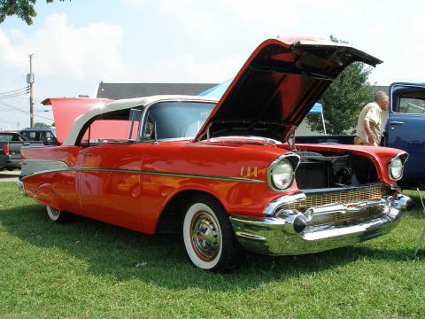 1998 Ford Crown Victoria - A classic red 1957 Chevrolet Bel Air convertible is displayed with its hoods open at an outdoor car show.