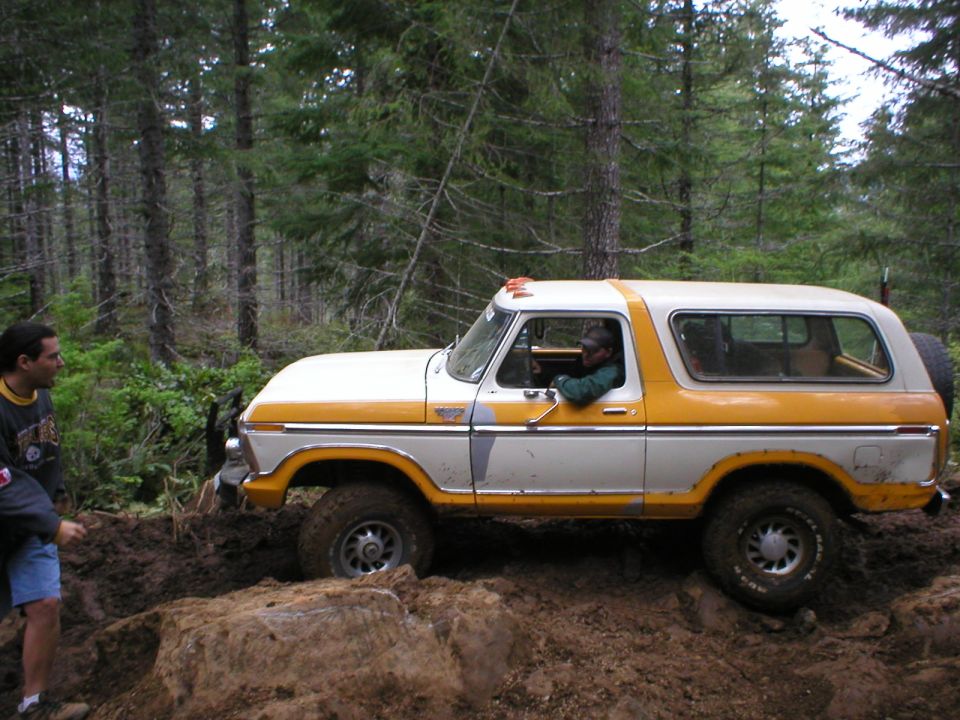 1978 Ford Bronco side view, white and yellow two-tone paint, off-roading in mud