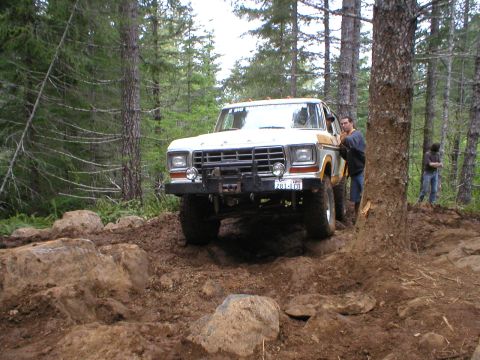 1978 Ford Bronco - A 1978 Ford Bronco tackles a challenging off-road course in a wooded area.
