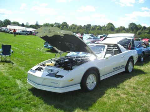 1984 Pontiac Fiero - A white 1984 Pontiac Trans Am is displayed with its hoods open at an outdoor event.