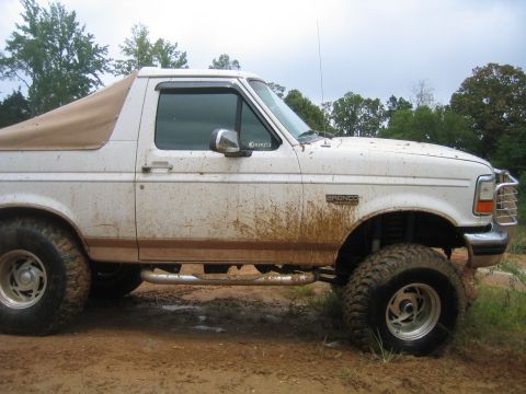 1996 Ford Bronco - This 1996 Ford Bronco is shown in a side profile, a tan soft top and significant mud splatter.