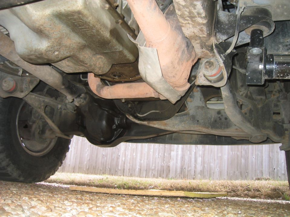 Underside of lifted 4x4 front axle, differential housing, radius arm and exhaust