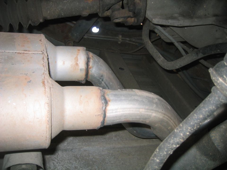 Underside view of exhaust system showing catalytic converter and welded pipe joint