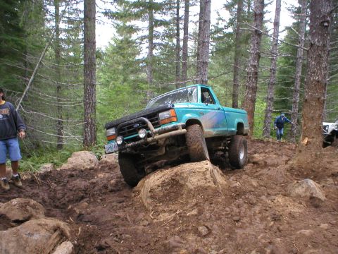 1978 Ford Bronco - This teal off-road SUV navigates a challenging muddy trail.