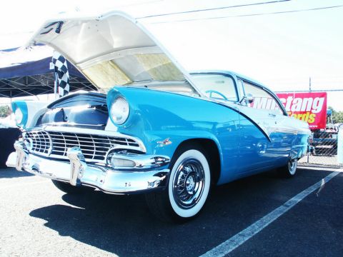 2001 Mercury Grand Marquis - A bright blue 1956 Ford Fairlane Crown Victoria is displayed with its hood open at a car show.