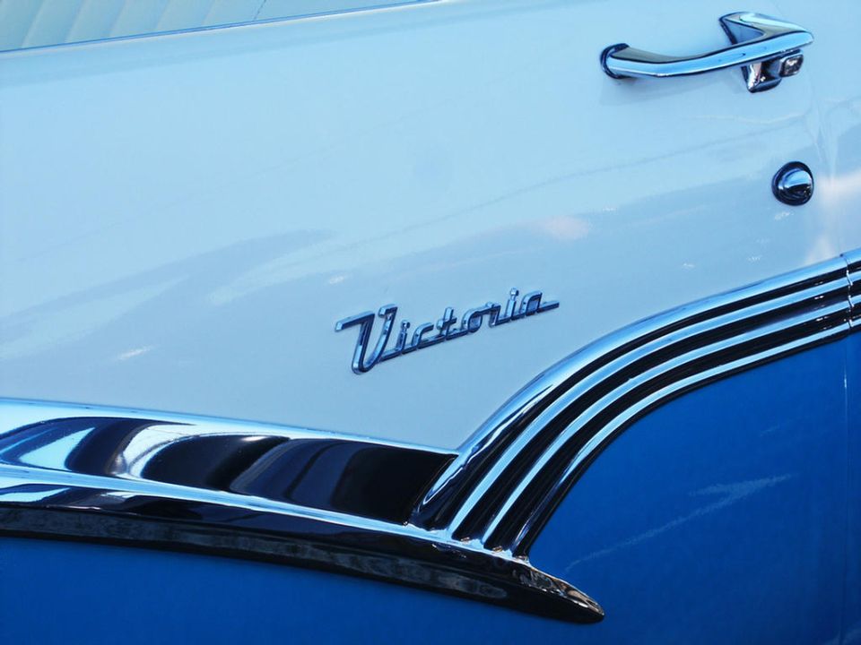 Chrome 'Victoria' emblem on a two-tone blue and white car door