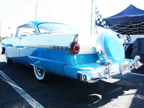 2001 Mercury Grand Marquis - A classic 1956 Ford Fairlane is displayed at a car show with a continental kit and checkered flags in the background.