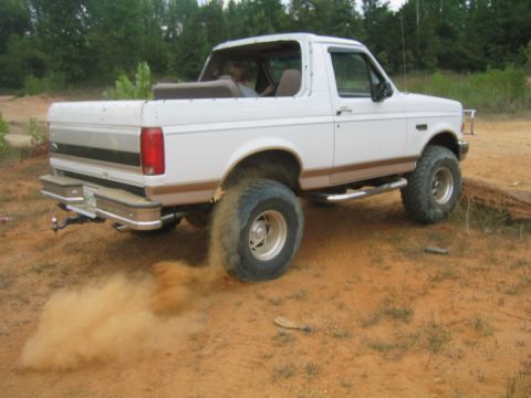 1996 Ford Bronco - This 1996 Ford Bronco is seen from the rear 3/4 angle, kicking up a cloud of dust as it drives off-road.