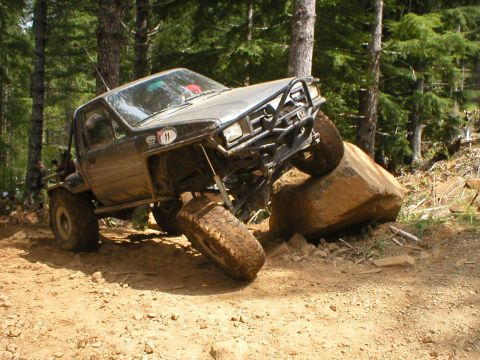 1978 Ford Bronco - This modified truck is navigating a challenging rocky terrain in a wooded area.