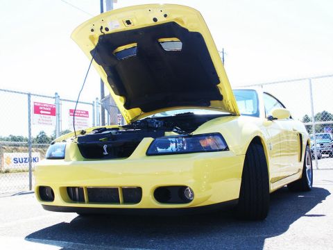 2001 Mercury Grand Marquis - A yellow Ford Mustang Cobra is displayed with its hood open, revealing the engine compartment.
