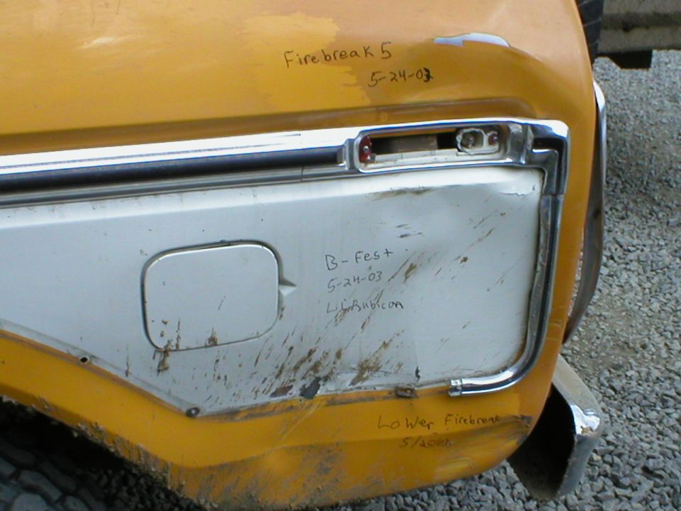 Yellow vehicle's rear quarter panel with chrome trim, gas cap door, and handwritten text