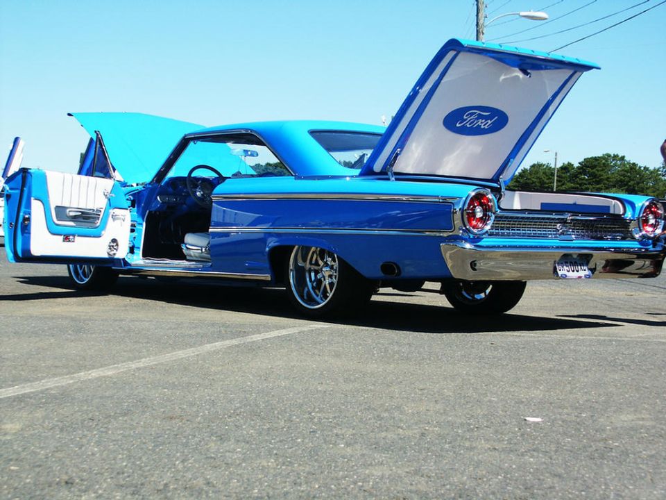 Blue classic Ford sedan, doors and hoods open. Ford logo visible in trunk lid