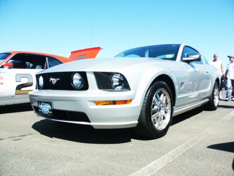 2001 Mercury Grand Marquis - A silver Ford Mustang is parked at an outdoor event, with another car visible to its left and people in the background.