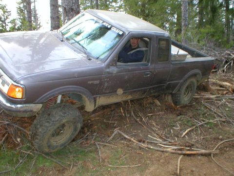 1978 Ford Bronco - A driver sits in a muddy Ford Ranger pickup truck, which appears to be stuck off-road.