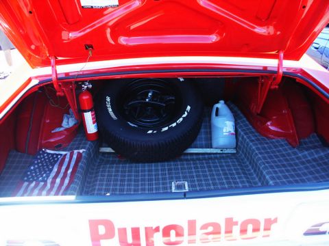 2001 Mercury Grand Marquis - The open trunk of a car reveals a spare tire, a fire extinguisher, and an American flag laid out on the checkered lining.