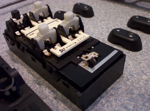 1998 Ford Crown Victoria - Close-up of a disassembled power window switch assembly with associated button caps.