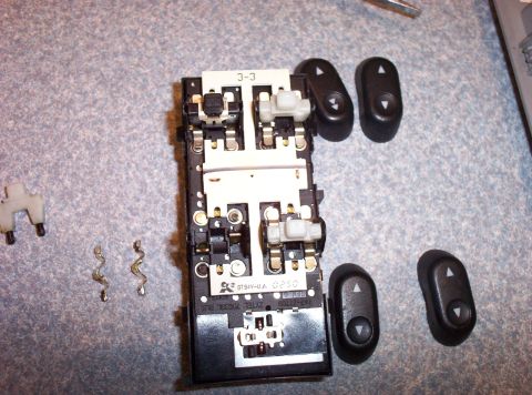 1998 Ford Crown Victoria - Car door window switch assembly disassembled, showing internal components and separate buttons.
