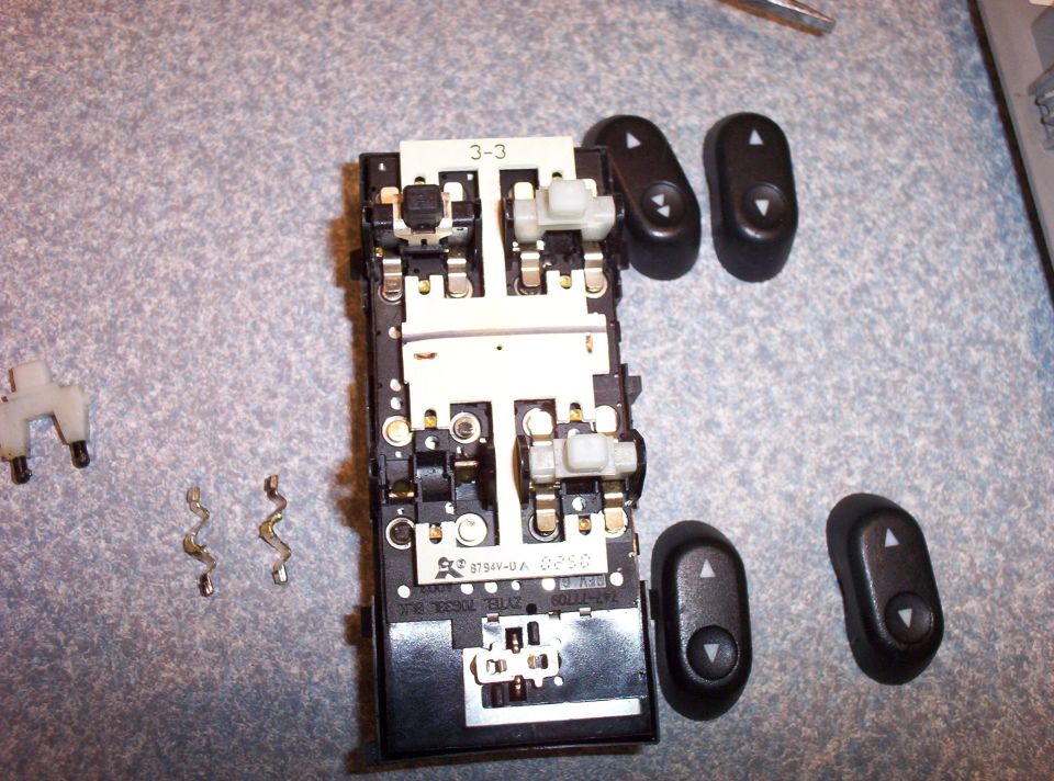 Disassembled car door window switch assembly with separate buttons and springs