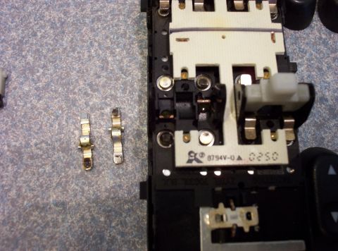 1998 Ford Crown Victoria - A disassembled electronic switch assembly from a car's interior is shown with loose metal connectors.