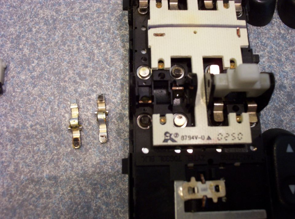 Close-up of car interior electronic switch assembly with two detached metal connectors