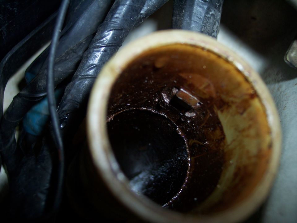Close-up of a dirty engine oil filler cap opening with visible grime and some wiring