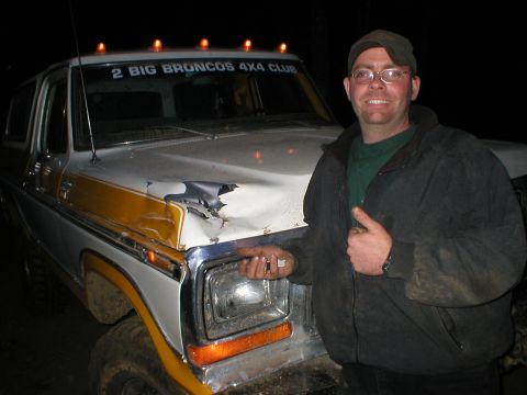 1978 Ford Bronco - Man poses with a 1978 Ford Bronco that has a dented hood and a prominent yellow stripe.