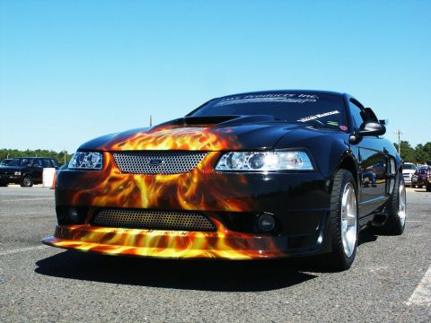 2001 Mercury Grand Marquis - This black car features a striking flame airbrush design on its hood and front bumper, seen at a car show.