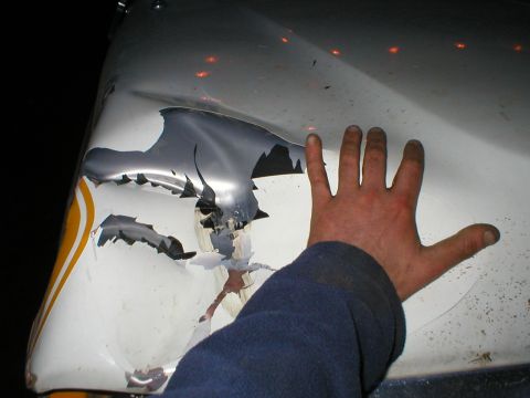 1978 Ford Bronco - Damaged vehicle fender with peeling paint and a hand for scale.