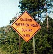 1968 Ford Mustang - A road sign warns drivers about potential water on the road during rainy conditions.