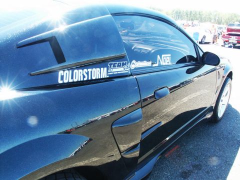 2001 Mercury Grand Marquis - A black car with racing decals is parked at an outdoor event with other vehicles visible.