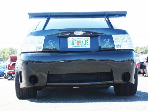 2001 Mercury Grand Marquis - Rear view of a Ford Mustang Cobra, showing its distinctive spoiler and dual exhaust pipes. Florida plate S63 4JE.