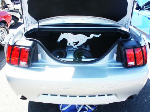 2001 Mercury Grand Marquis - The trunk of a silver Ford Mustang is open, revealing a custom audio setup and a running horse emblem.