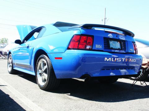 2001 Mercury Grand Marquis - A blue Ford Mustang Mach 1 is parked at a car show, with its hood up and a spoiler on the trunk.