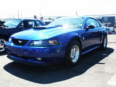 2001 Mercury Grand Marquis - A blue Ford Mustang is seen at a car show, parked next to another vehicle.