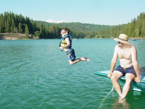 1986 Ford Bronco - A boy leaps into a lake while a man watches from the side of a boat.