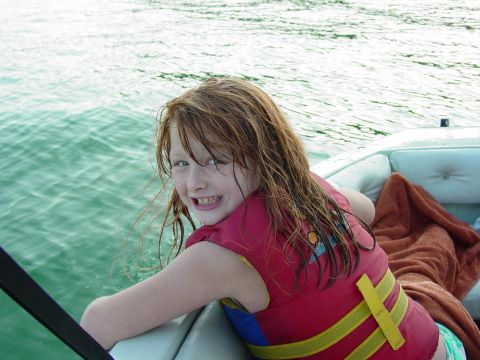 1986 Ford Bronco - A young girl wearing a life jacket smiles while sitting in a boat on the water.