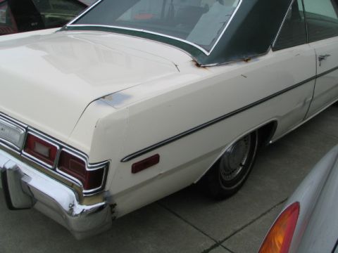 1975 Dodge Dart - The rear end of a white sedan with a green vinyl roof shows some rust near the rear window trim.