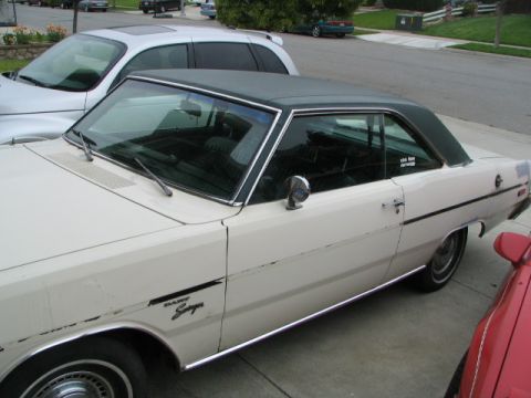 1975 Dodge Dart - A white coupe with a black vinyl roof and a 'Dart Swinger' badge is parked next to another vehicle.
