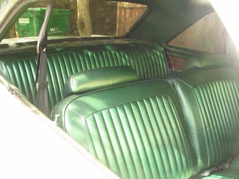 1975 Dodge Dart - The interior of a car features green vinyl seats and a view of trash cans outside the rear window.
