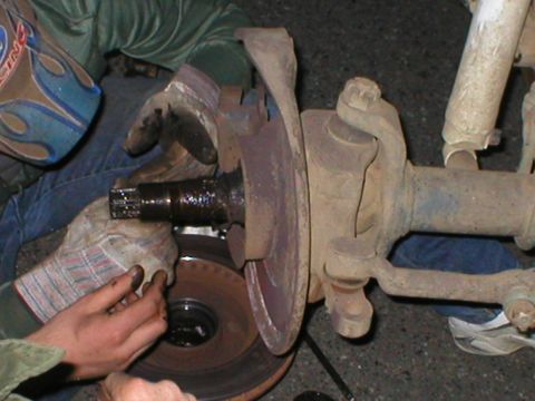 1978 Ford Bronco - Close-up of a vehicle's front axle assembly, showing brake rotor and suspension parts during maintenance.