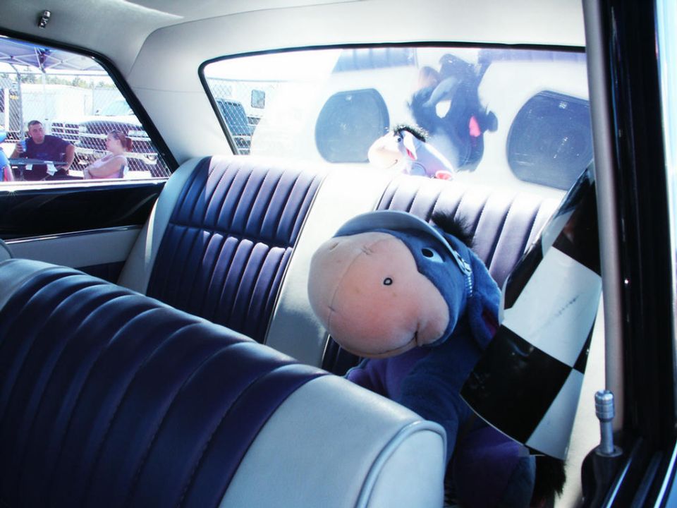 Interior of a classic car with plush Eeyore toys on the back seat and a checkered flag