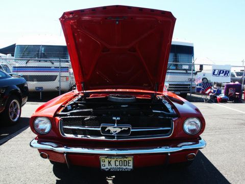 2001 Mercury Grand Marquis - A red 1965 Ford Mustang is displayed with its hood open at a car show.