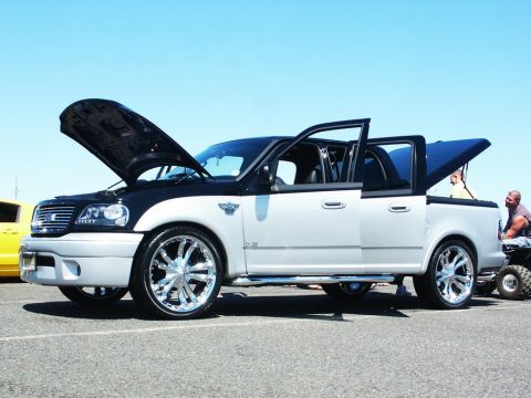 2001 Mercury Grand Marquis - A customized pickup truck is displayed with its hood and doors open, chrome wheels and a two-tone paint scheme.