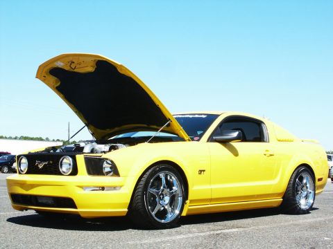 2001 Mercury Grand Marquis - Yellow Ford Mustang GT parked outdoors with hood up, revealing the engine bay.