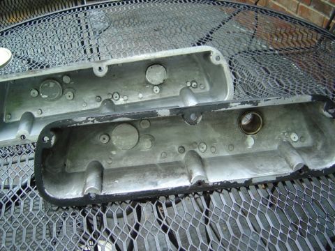 1986 Ford Bronco - Two aluminum valve covers are shown resting on a metal table, one with a black gasket.
